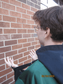 a person standing in front of a brick wall with the date 03/24 2024