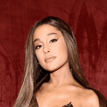 ariana grande is standing in front of a red background wearing a black dress .