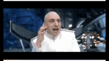 a bald man in a white suit is talking to someone