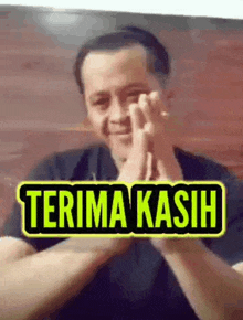 a man is clapping his hands with a sign that says terima kasih .