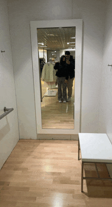 a man and woman are taking a picture of themselves in a dressing room mirror