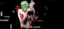 a man with a green mask is holding a trophy and saying `` thank you '' .