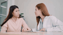 a woman in a pink shirt is talking to a doctor in a white coat