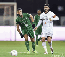 two soccer players with one wearing a green shirt with saudia on it