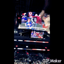 a man in a red shirt is sitting in the stands at a basketball game with the number 1 on his shirt .