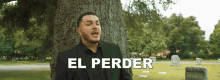 a man in a suit stands next to a tree in a cemetery with el perder written on the bottom