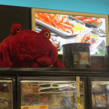 a red stuffed octopus sits on top of a display case with a sign that says save