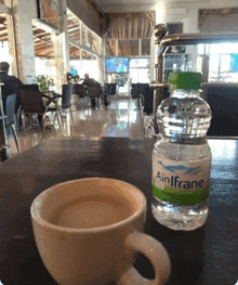 a bottle of ainlfrane water next to a cup of coffee