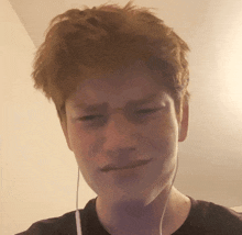 a young man with red hair is wearing ear buds and making a funny face