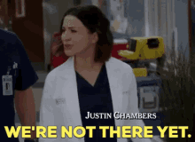 a woman in a lab coat is standing next to a man in scrubs and says `` we 're not there yet . ''