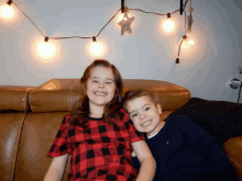 a boy and a girl are sitting on a couch and smiling