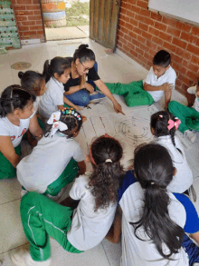 a group of children sitting on the floor with a teacher pointing at a drawing