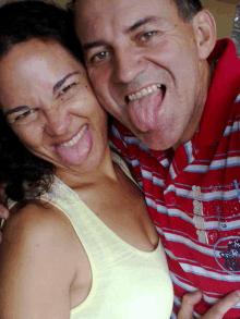 a woman sticking her tongue out next to a man wearing a striped shirt