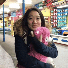 a woman holding a pink teddy bear in front of a store