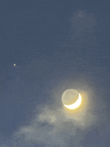 a crescent moon in a cloudy sky with a star in the background