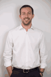 a man wearing a white shirt and black pants is smiling for the camera