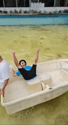 a man is laying on his back in a boat with his legs in the air