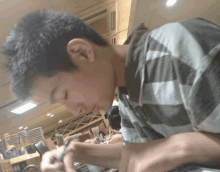 a young man in a striped shirt is writing with a pen