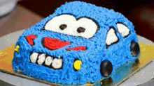 a cake in the shape of a blue car with a face on it .