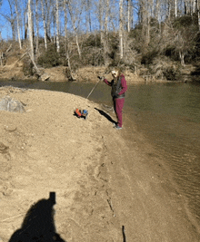 a woman stands on a sandy beach near a river