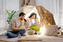 a family is sitting under a tent reading a book