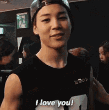 a young man wearing a baseball cap and a black shirt says i love you