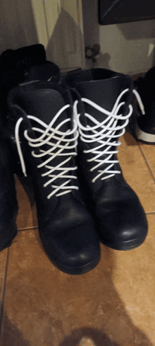 a pair of black boots with white laces on a tile floor