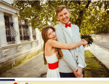 a man in a suit and bow tie is hugging a woman in a white and red dress