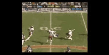 a group of football players standing on a field with a referee and a scoreboard behind them that says nfl on it