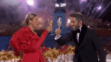 a man and a woman are toasting with champagne in front of a sign that says " feliz 2019 "