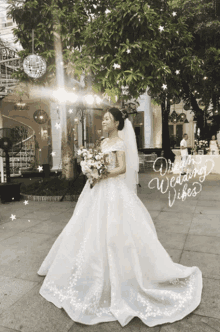 a woman in a wedding dress is standing in front of a tree with the words dream wedding vibes written on the ground