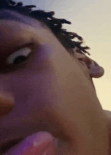 a close up of a person 's face with dreadlocks and a purple background .