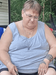 a woman with glasses and a tattoo on her arm is sitting on a couch .