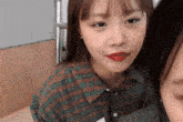 a girl in a plaid shirt with red lips looks at the camera