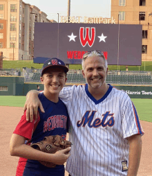 a man in a mets jersey stands next to a young boy