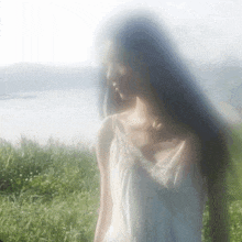 a woman in a white dress is standing in a field of grass .