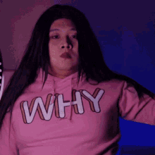 a woman wearing a pink hoodie that says why on it