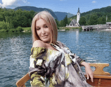 a woman sits in a boat in front of a lake with mountains in the background