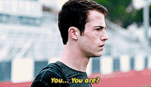 a young man with a backpack is standing in front of a stadium and asking " you ... you are "