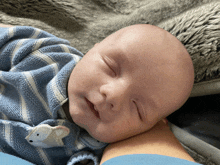 a baby wearing a blue and white striped outfit is sleeping on a blanket