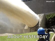 a man wearing a blue hard hat is standing in front of a large pipe that is blowing smoke .