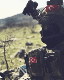 a soldier with a helmet and a flag on his chest is holding a rifle .