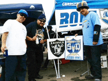 a group of men standing in front of a raiders sign