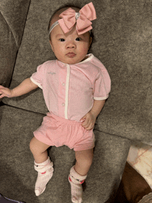 a baby wearing a pink shirt and shorts is laying down on a couch