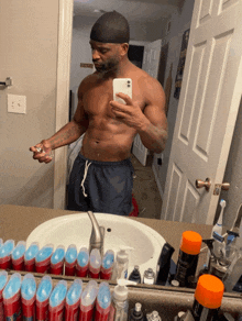 a man taking a picture of himself in a bathroom mirror with bottles of deodorant on the counter