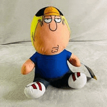 a stuffed toy of peter griffin from family guy is sitting on a blanket .