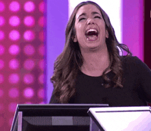 a woman is laughing while standing in front of a monitor