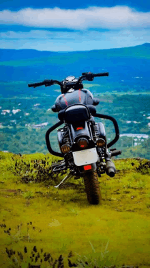 a motorcycle is parked on a grassy hillside with a mountain in the background