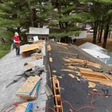 a man is standing on the roof of a house looking at a phone