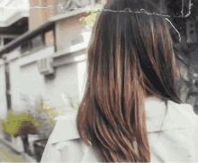 a woman with long hair is standing in front of a building and looking at the camera .